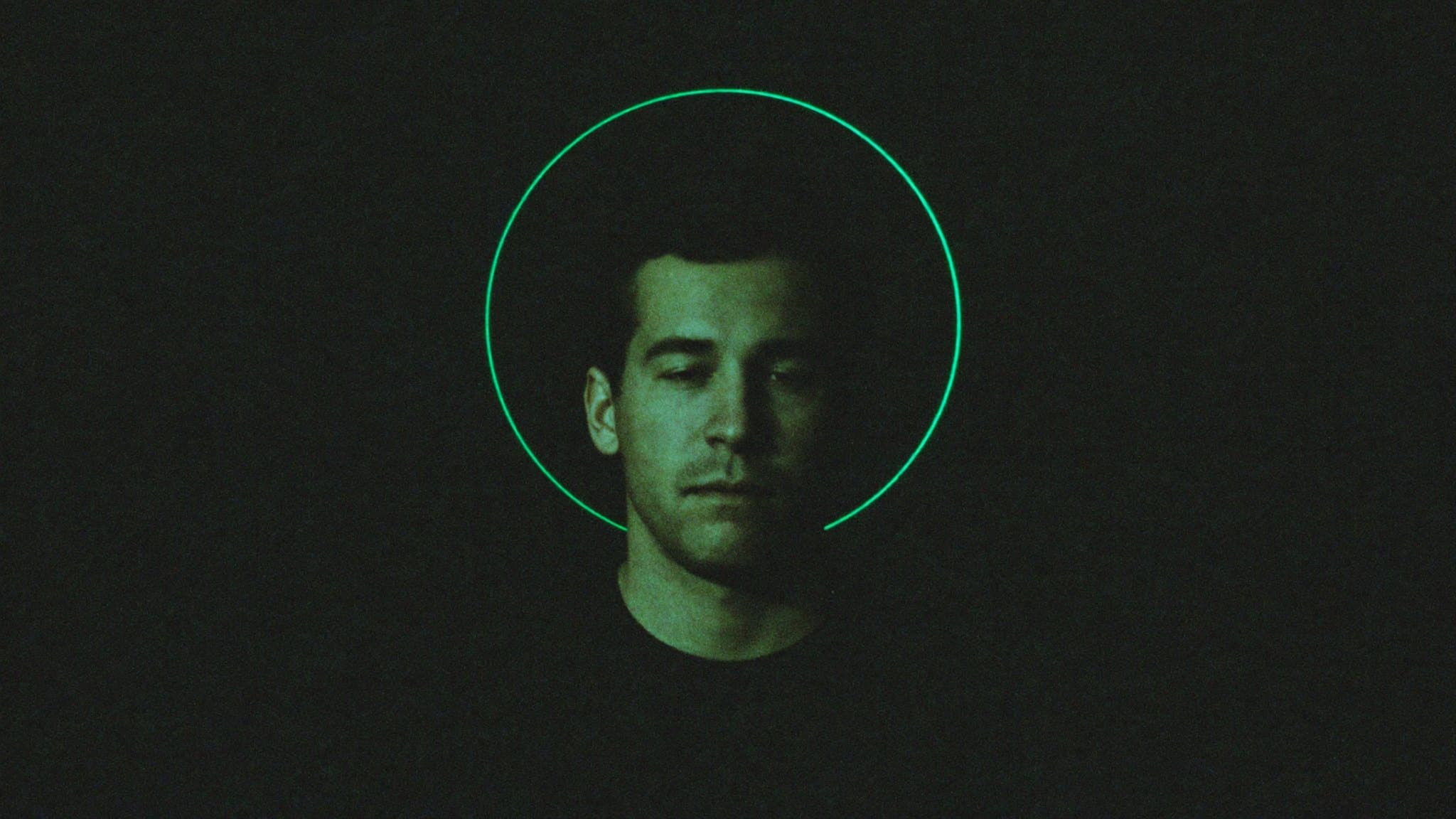 A portrait lit by a thin circular green halo against black